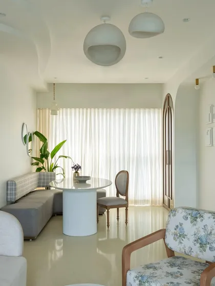 The open layout of this home creates a feeling of spaciousness and light. The dining nook flows seamlessly into the living area, with a cohesive palette of whites, greys, and natural wood tones tying the different zones together.