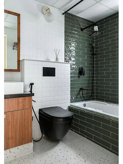Another shot of the master bathroom, showing how the sleek black fixtures, including the toilet and showerhead, provide a bold contrast to the green and white tiles.