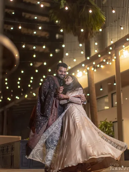 A romantic night portrait with the couple dancing under a canopy of fairy lights. The movement in the bride's dress adds a dynamic feel.