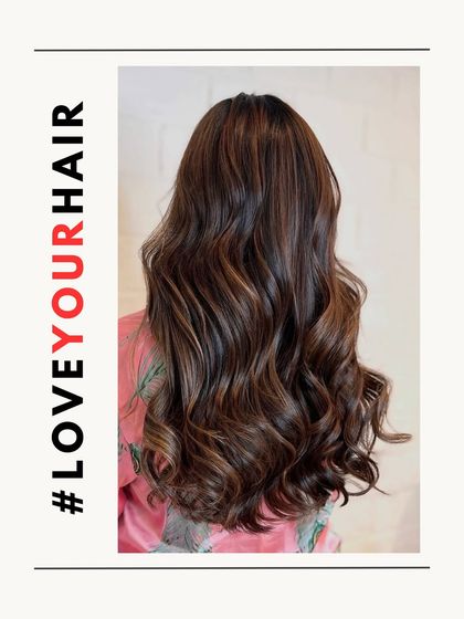 A stunning example of a brunette balayage. The image showcases the back of the head, with long, flowing waves and expertly blended highlights.