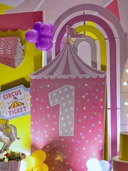 A detailed shot of the circus tent backdrop for a first birthday carnival. The number '1' is prominently featured, along with a circus ticket sign and popcorn prop detail.