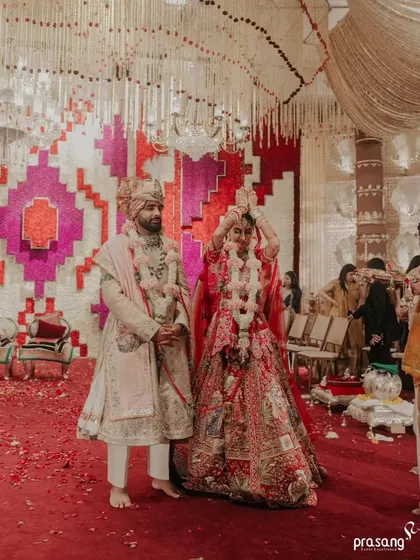 A moment of ritual during the ceremony, with the couple standing before the grand floral wall. The scale of the decor emphasizes the significance of the moment.