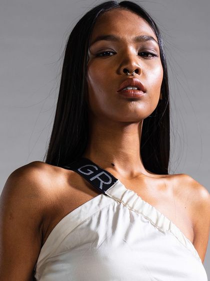 This look features a warm, bronzed skin tone and a glossy lip, paired with pin-straight hair. The overall effect is a chic and contemporary style suitable for a fashion editorial.