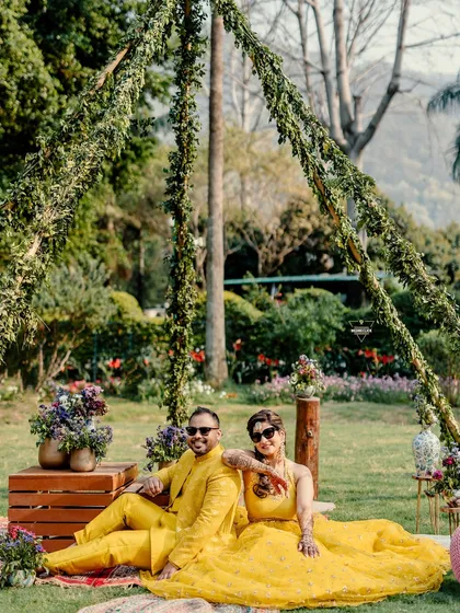 A relaxed and cool portrait of the couple sitting in a picnic-style setup at their Mehendi, looking effortlessly stylish.