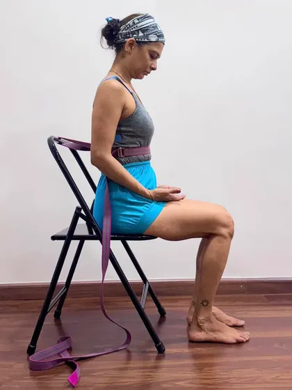 This image demonstrates the use of a belt in a seated pranayama preparation. The belt around the lower ribs provides feedback to prevent them from hardening, which helps the diaphragm to relax and creates the correct internal state for breathwork.