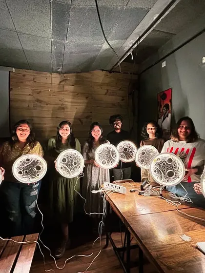 A fantastic group photo of participants proudly holding their finished moon lamps, all lit up and shining bright.