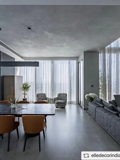 The open-plan living and dining area of the duplex, showing how the consistent use of grey tones and minimalist furniture creates a cohesive and expansive feel.