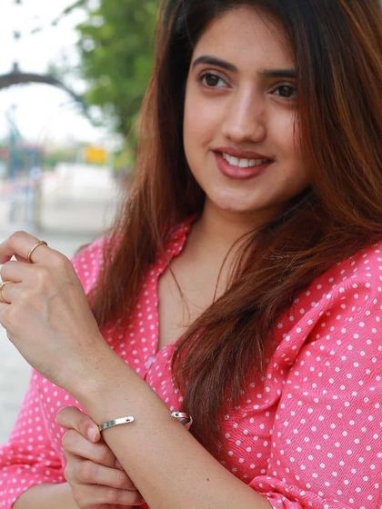 Another angle showing the woman in pink admiring her custom-engraved bracelet, a perfect accessory for a bright, casual outfit.