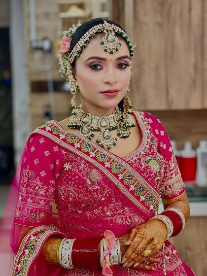 This bride opted for a vibrant pink and green lehenga. We complemented her outfit with soft pink makeup, green-accented jewelry, and an elegant floral bun to create a cohesive and fresh bridal look.