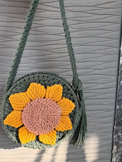 A close-up of our macrame sunflower bag. The detail in the petals is all hand-knotted, making each bag unique. It's a perfect statement piece for a vacation or a day out.