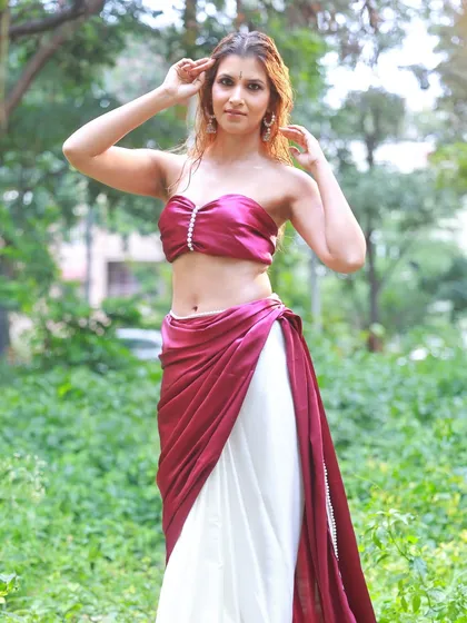 A full-length outdoor shot that captures the complete look of the dual-tone saree. The model's pose is confident and relaxed, fitting the natural setting.