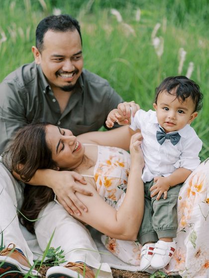A family enjoying a relaxed moment in a field. The baby's curious expression is adorable.