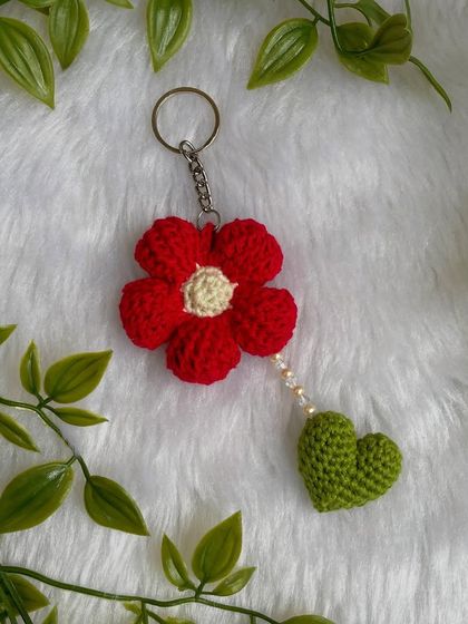 The flower and heart keychain lying on a soft white background. It’s a beautiful, custom-made accessory.