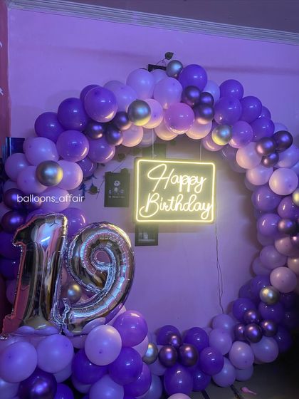 A close-up of the 'Happy Birthday' neon sign inside the purple balloon ring for the 19th birthday.