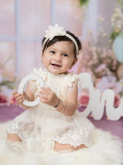 A happy smile while holding the "O" from the "One" sign. A perfect first birthday photo.