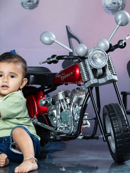 This future rockstar is getting ready for his first concert, sitting by his motorcycle and microphone. The setup includes musical notes and disco balls for a full rock show vibe.