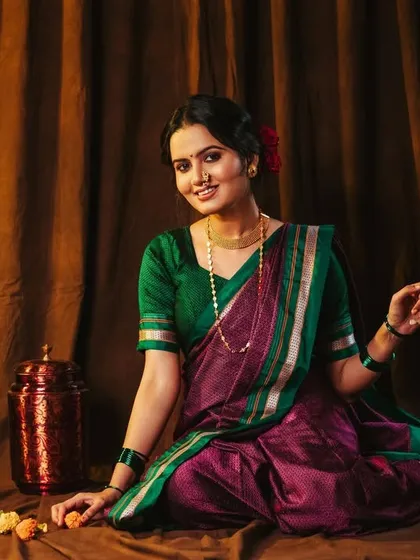 A seated portrait with a warm smile. The props, like the brass pot and marigold flowers, add to the traditional setting.