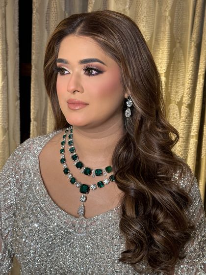 A beautiful portrait shot, highlighting the flawless makeup and the contrast between the silver outfit and the green emeralds.