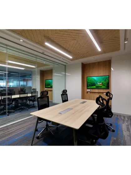 A modern glass-walled conference room equipped with integrated technology. The design balances transparency with privacy, featuring patterned ceiling details and striped carpeting for a sophisticated finish.