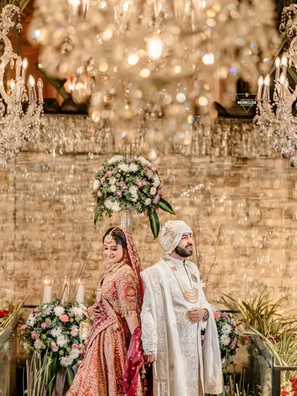A regal portrait of the couple standing back-to-back under stunning crystal chandeliers, creating a look of timeless elegance.