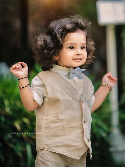 A joyful, candid shot of the same little gentleman. His happy expression and animated pose capture the wonderful energy of a toddler exploring the outdoors.