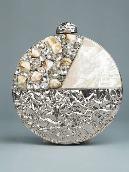 A modern take on the circular clutch, this piece is divided into sections of textured silver-tone metal, mother of pearl, and a mosaic of sparkling stones. It's a versatile accessory for any evening event.
