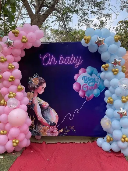 An outdoor "Oh Baby" gender reveal backdrop. The design uses a custom printed background with pink and blue balloon arches on either side, perfect for a garden or backyard celebration.