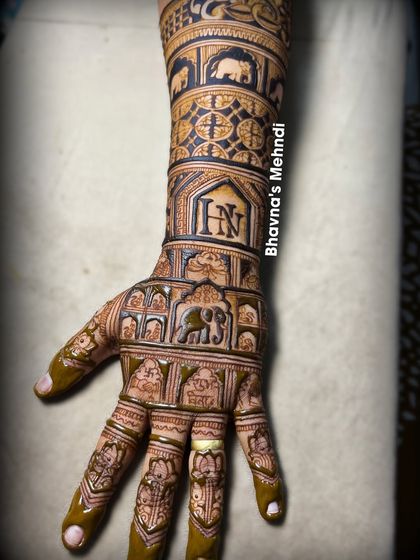 This full back hand design is a masterpiece of traditional art. It features bands of elephants and geometric patterns, with the couple's initials taking center stage in an ornate frame.