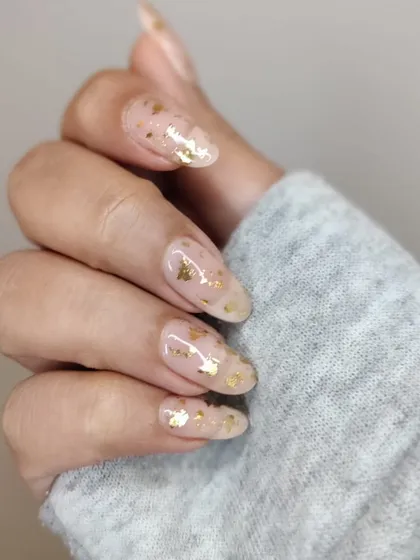 A delicate manicure with gold foil flakes suspended in a clear gel. This creates a beautiful, fragmented gold leaf effect that is both rustic and glamorous.