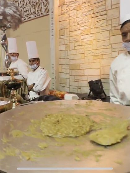 A chef preparing a dish on a large flat tawa at a live station. This method is perfect for a variety of vegetarian dishes and ensures the food is served piping hot.