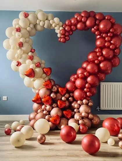 This large, heart-shaped balloon arch is a popular choice for Valentine's Day. The mix of cream, red, and metallic rose gold balloons creates a dramatic and romantic photo opportunity for any room.