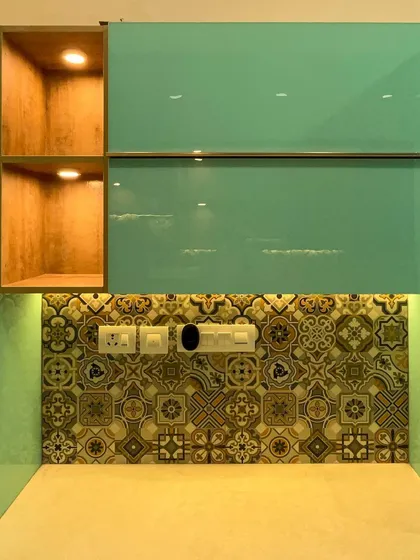 A detail shot showing our precise installation of a patterned tile backsplash and an open, wood-finish shelf with integrated lighting. We ensure that electrical points and finishes are perfectly aligned for a clean result.