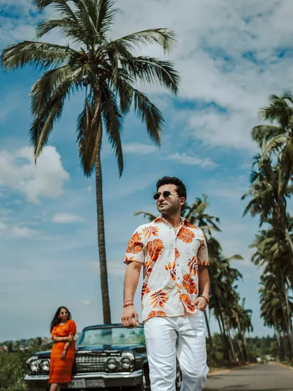 A stylish pre-wedding shoot on the coast of Goa. The couple poses with a vintage car against a backdrop of palm trees and a clear blue sky, showcasing our ability to create fashionable and fun pre-wedding stories.