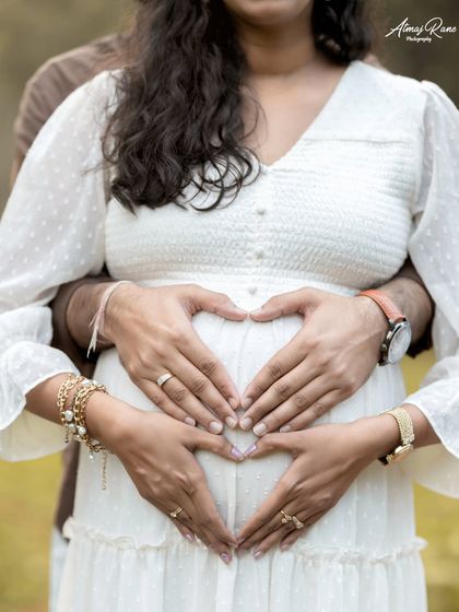Both parents' hands join to form a heart over the baby bump. This popular pose is a simple yet powerful way to symbolize the love and protection awaiting the new arrival.