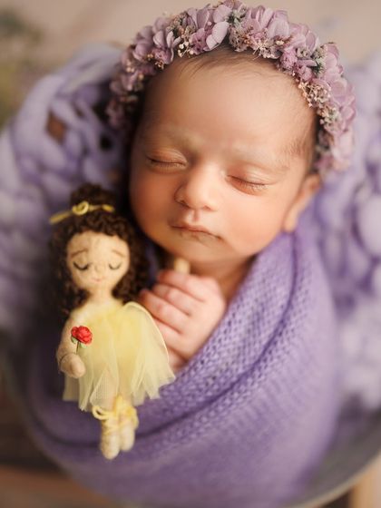 This little princess looks so lovely in lavender. The delicate floral crown and the tiny ballerina doll she's holding make this a truly unique and precious portrait.