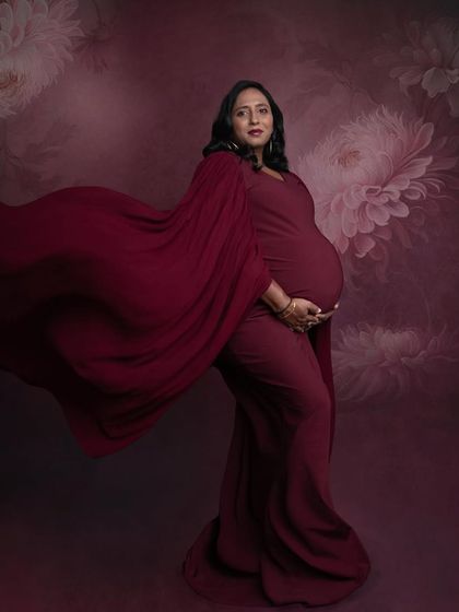 A dramatic profile shot with the red gown flowing behind her. The rich color and the floral painted backdrop create a very artistic and high-fashion look.