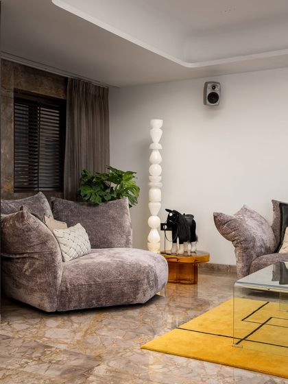 Another angle of this plush living room, showcasing the comfortable, oversized seating that invites relaxation. The design balances soft textures with bold art and a geometric rug, creating a dynamic yet cozy atmosphere.