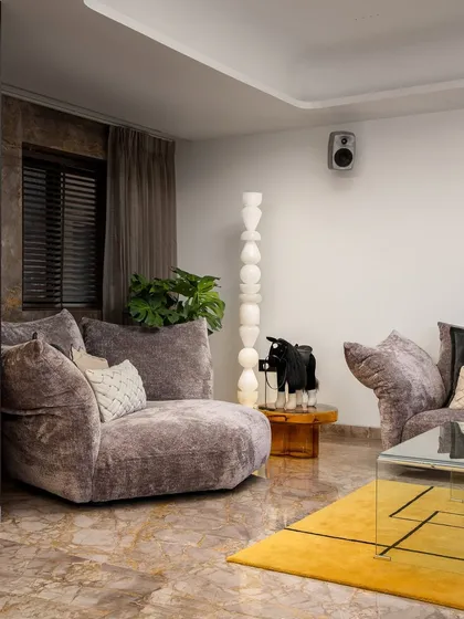 Another angle of this plush living room, showcasing the comfortable, oversized seating that invites relaxation. The design balances soft textures with bold art and a geometric rug, creating a dynamic yet cozy atmosphere.