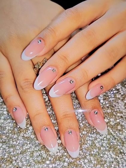 The epitome of classic elegance. A perfect French manicure on long, almond-shaped nails, with a single tiny rhinestone at the base of each nail for a subtle sparkle.