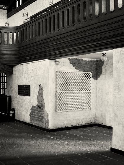 An alcove featuring distressed walls, a lattice screen, and a dark wood balcony overhead. This composition of textures and layers is central to the design.