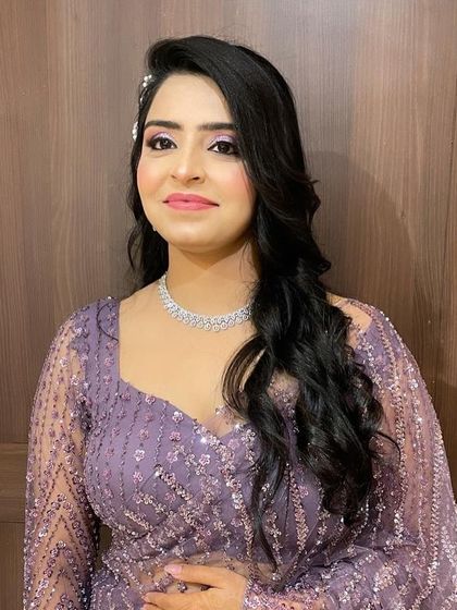 The client looks radiant with her party-ready hair and makeup. The side-swept style is flattering and elegant.