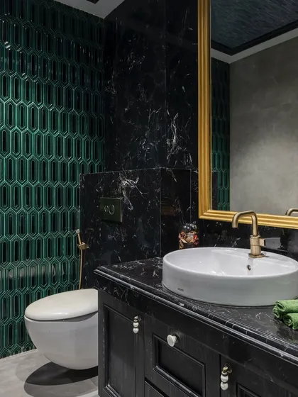 A close-up of the bathroom in 'The House of Arcs', showing the detail of the emerald green tiles and the black marble vanity.