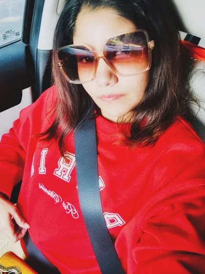 A car selfie in a bright red sweatshirt and oversized sunglasses, capturing a fun weekend vibe.