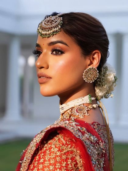 The golden hour light beautifully captures the details of the maang tikka and the side profile of the bride.