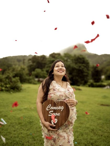 A joyful shot of the mom-to-be looking up as confetti falls around her, holding a "Coming Soon" sign. A perfect picture of celebration.