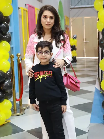A mother and son stand by the entrance of a racing-themed party, ready for a day of fun.