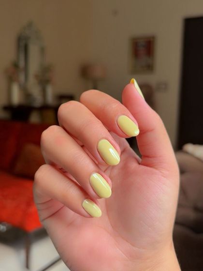 A beautiful butter yellow gel polish on short, oval nails. A soft and cheerful color.