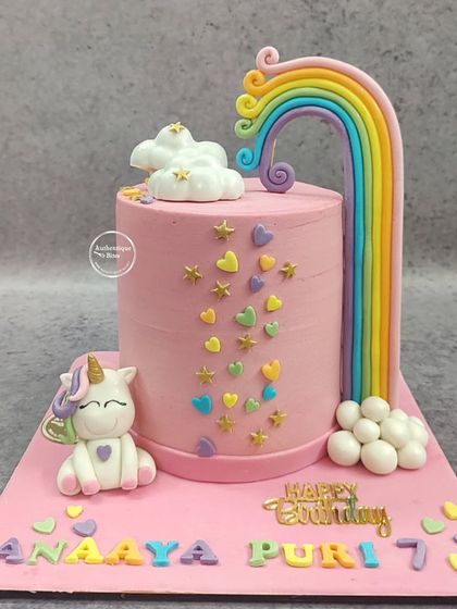 A lovely unicorn and rainbow cake. This design features a tall, flowing rainbow, a sweet unicorn figure, and a cascade of colorful hearts and stars.