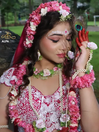 A serene portrait of the Radha makeover. The look is enhanced with a peacock feather, symbolizing the connection to Krishna, and soft, pink-toned makeup.
