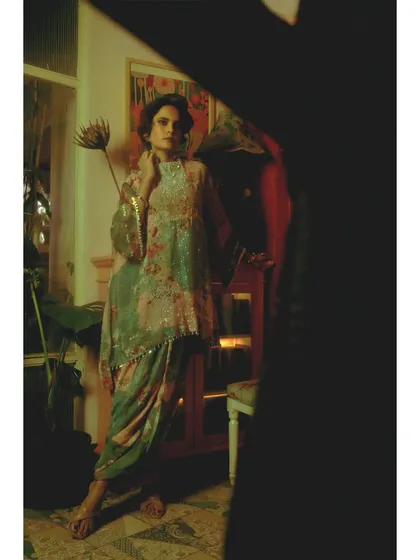 From 'Chapter 5: Visitors of the Past'. The styling combines a delicate, embellished traditional top with a modern draped skirt, showing the fusion of past and present. The framing through a dark foreground creates a sense of being observed.